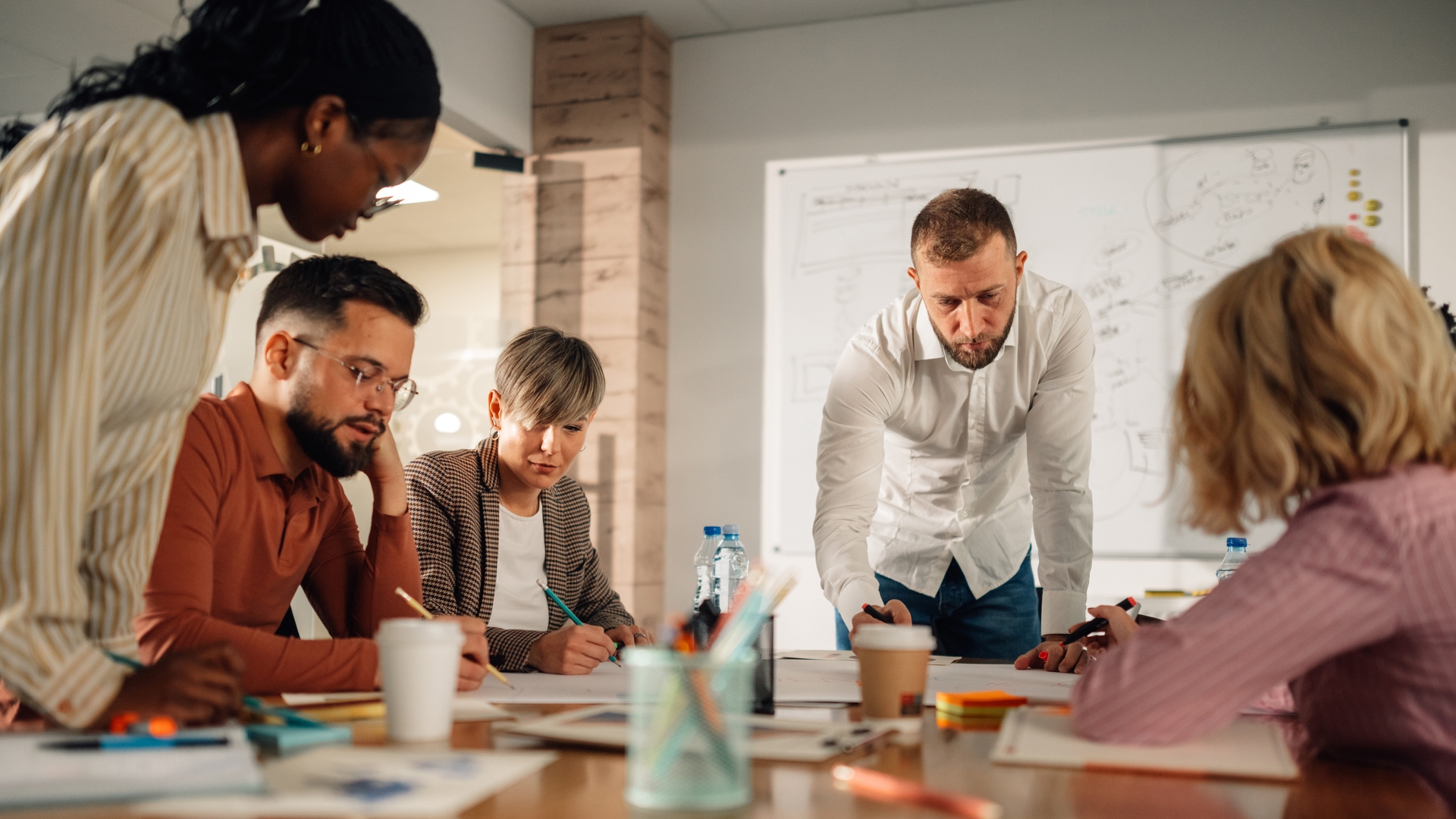 A group of professionals sitting around a table and writing.