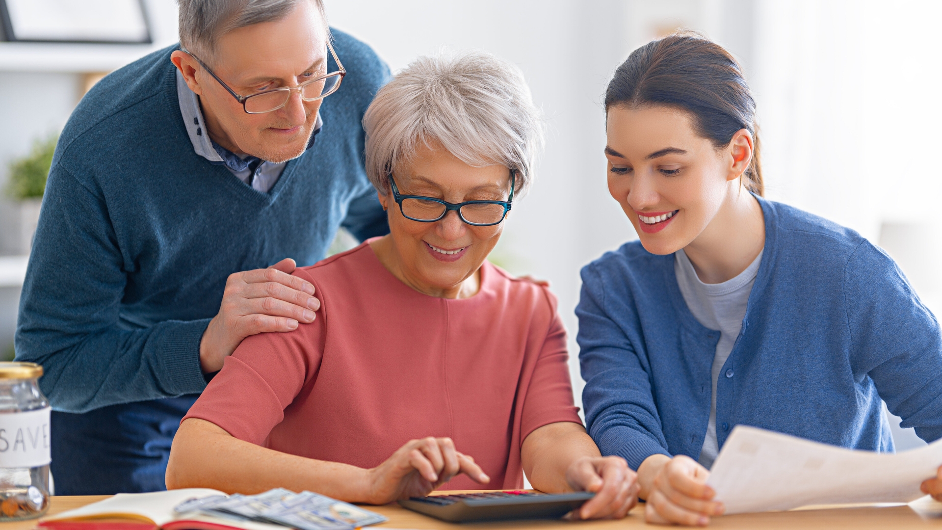 An older couple and a younger woman sitting together and using a calculator.