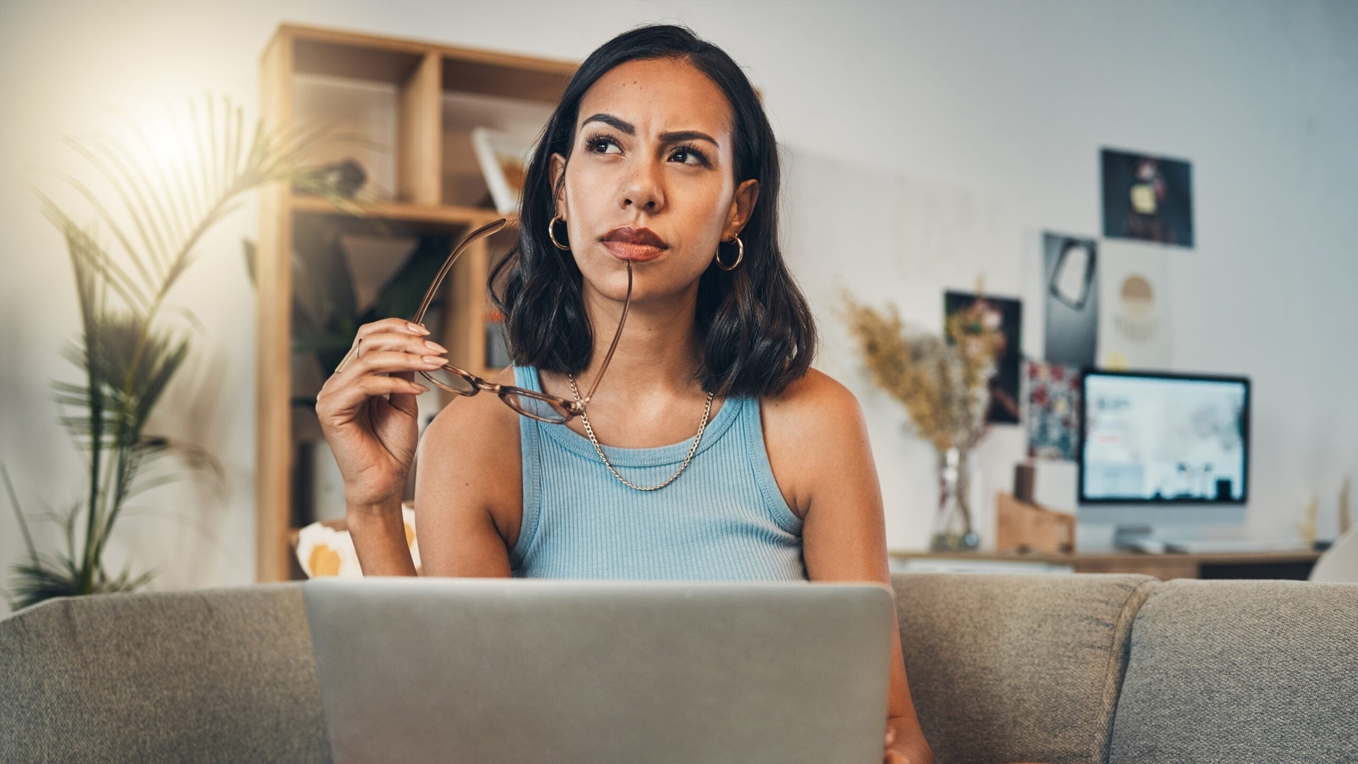A young woman sits on a couch with her laptop computer in her lap
