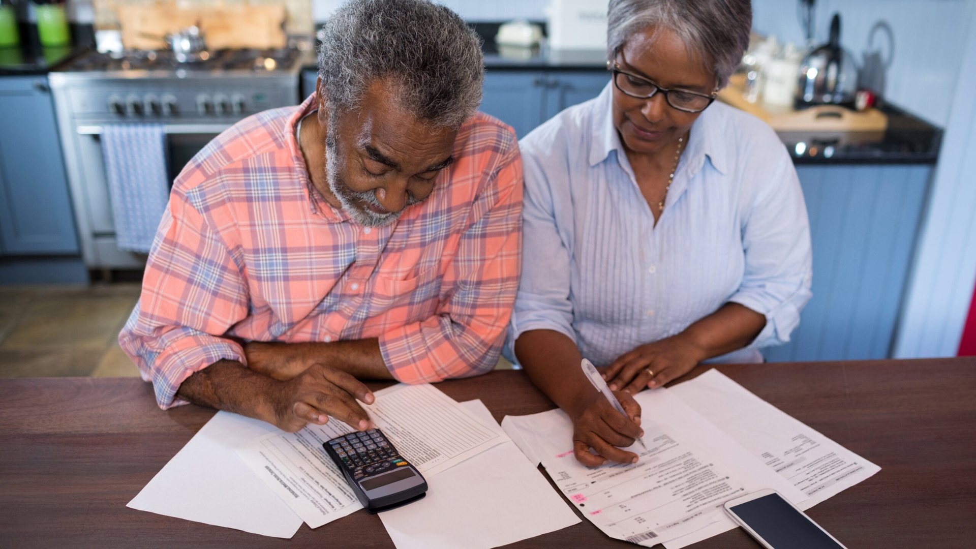 High angle view of couple using calculator at a table.