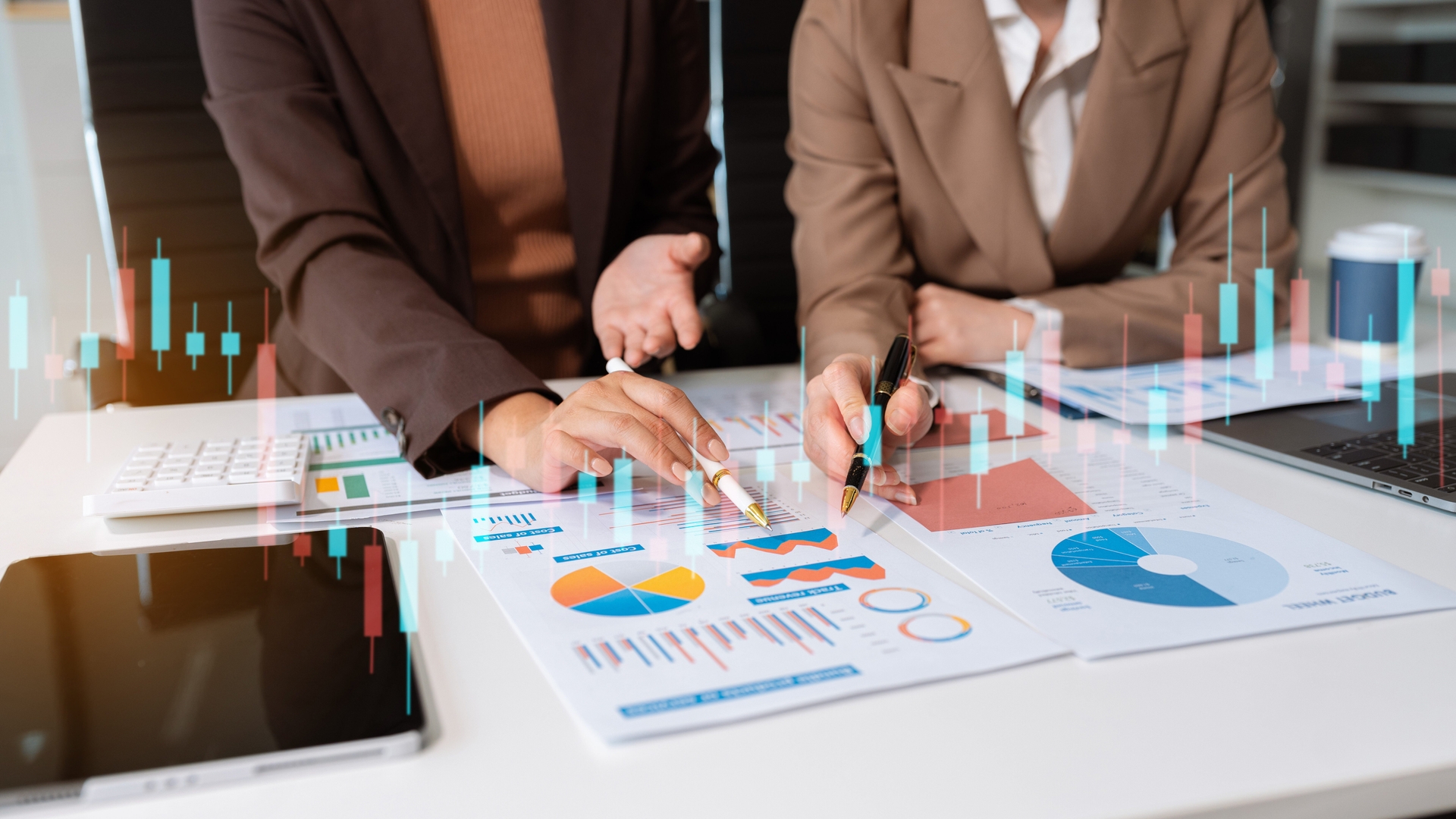 Two people in business attire discuss charts and graphs at a table with a tablet, calculator, and digital data overlay, analyzing the market with precision.